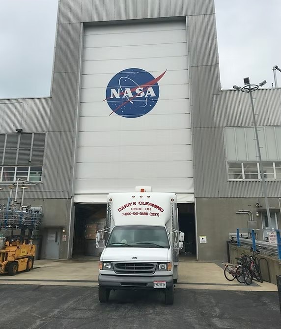 A Darr's Cleaning box truck lettered with the Clyde address and toll-free number, parked at the loading dock of a large research facility