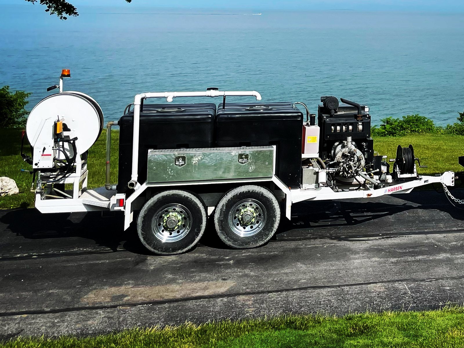 A Darr's Cleaning high-pressure jetting trailer, its hose reel, water tanks, engine and pump on a twin-axle frame, parked above Lake Erie