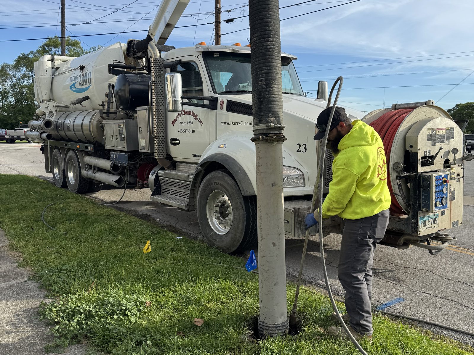 A Darr's Cleaning crew member working the hose reel of the Jet-Vac combination unit at a roadside opening