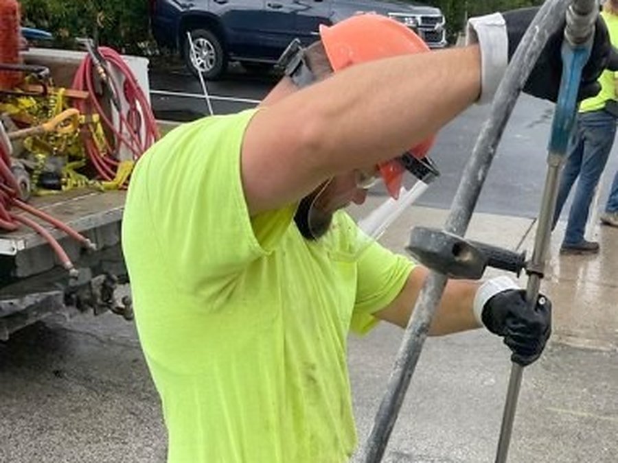 Crew member feeding a locating rod into an access hole